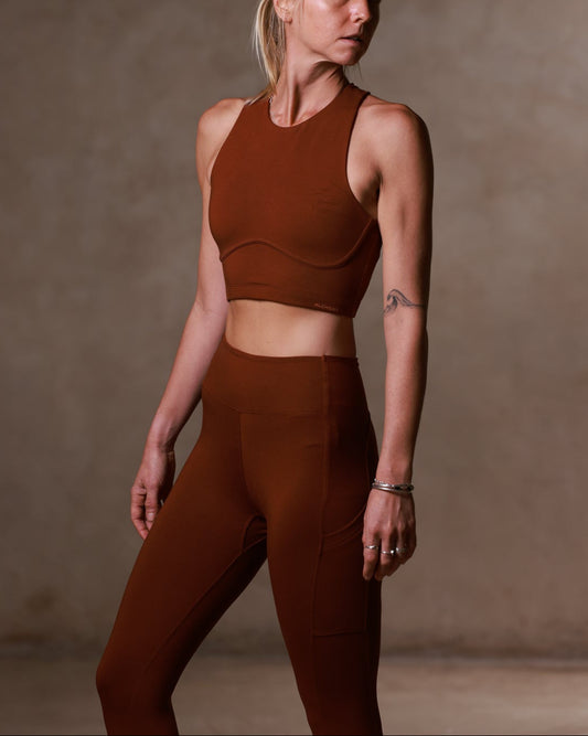 Woman wearing a brown sports bra and leggings against a neutral background