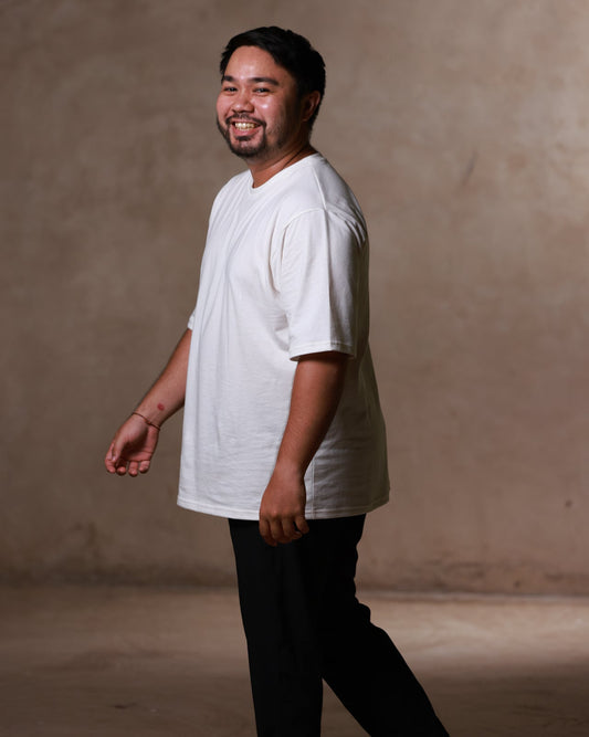 Man wearing a white shirt and black pants against a beige background