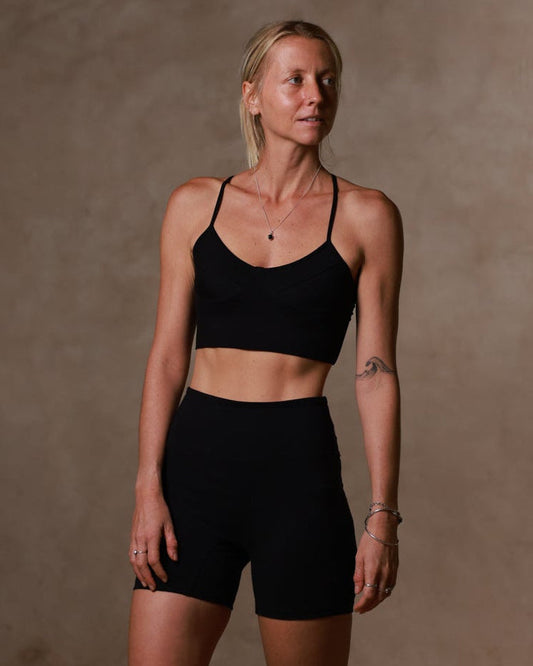 Woman wearing a black sports bra and shorts against a brown background