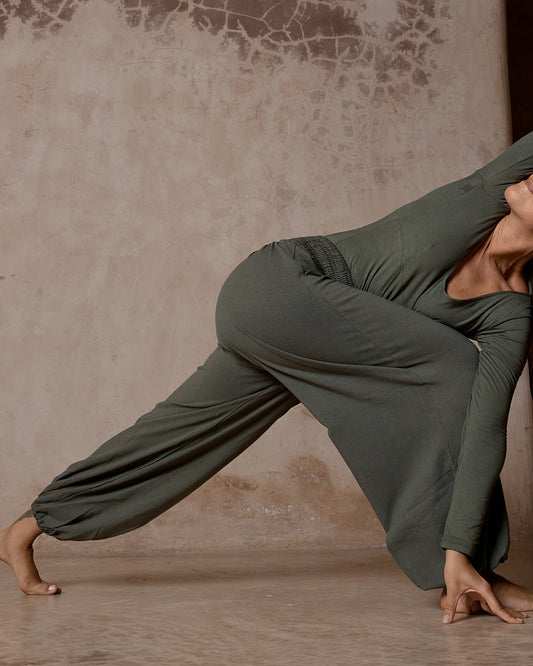 Person in a green outfit performing a yoga pose against a textured wall.