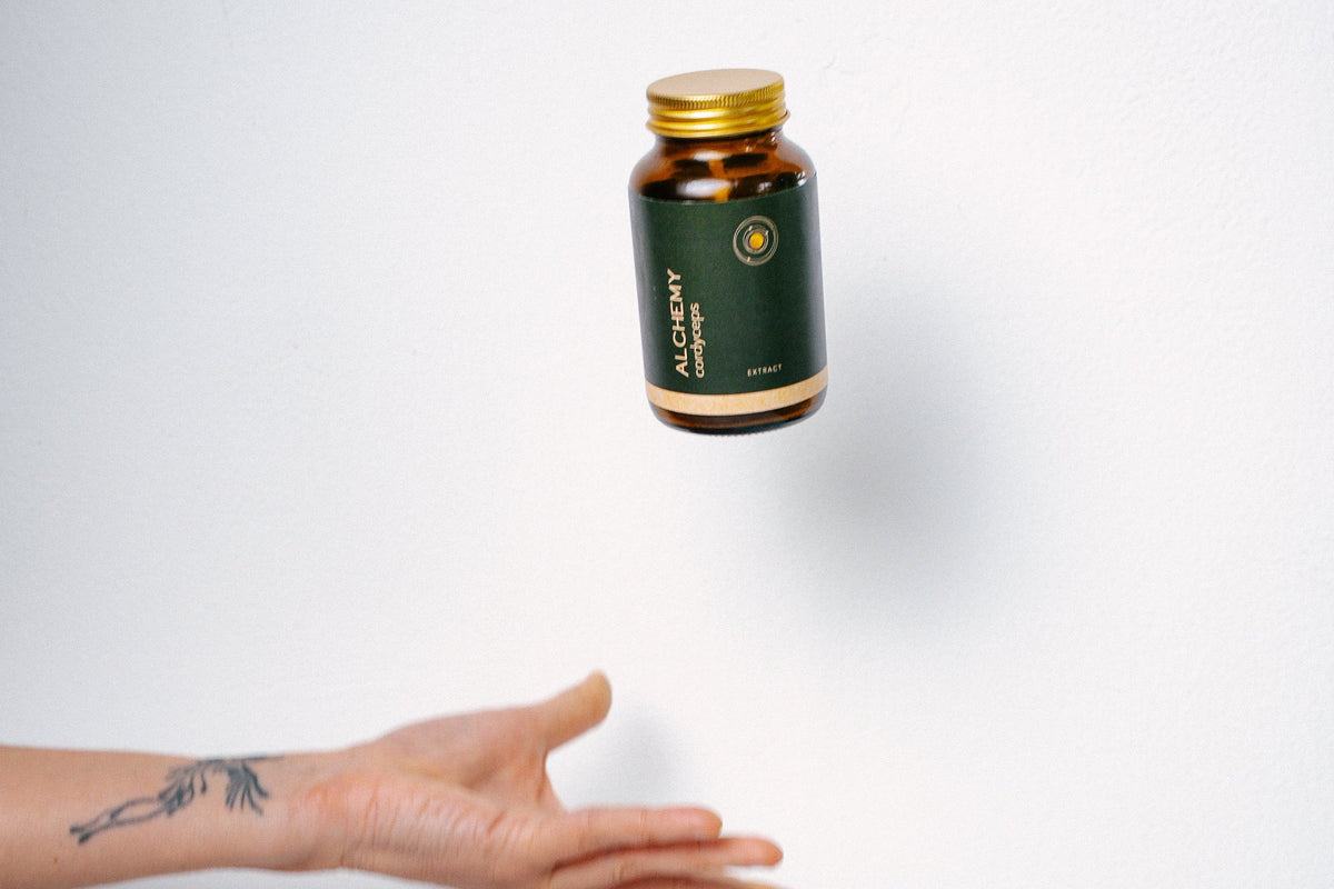 Hand reaching out towards a bottle of supplements on a white background