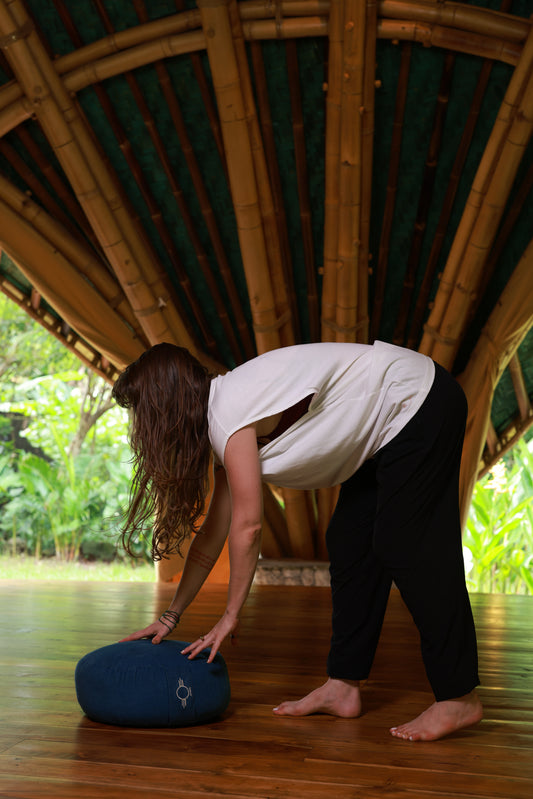 Person practicing yoga in a bamboo structure with a blue yoga mat